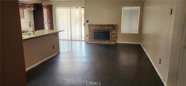 unfurnished living room with a brick fireplace, dark hardwood / wood-style floors, and sink