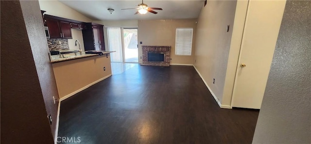 kitchen with lofted ceiling, ceiling fan, dark hardwood / wood-style floors, tasteful backsplash, and a fireplace