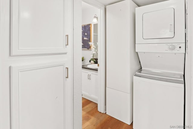 washroom featuring light hardwood / wood-style floors and stacked washer and clothes dryer