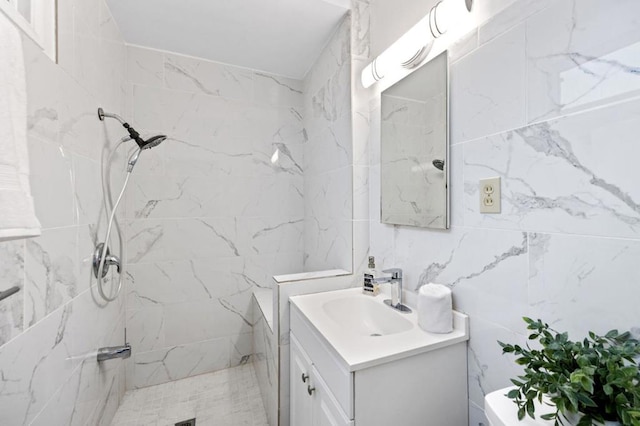 bathroom with vanity, tile walls, toilet, and tiled shower