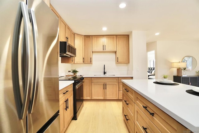 kitchen with appliances with stainless steel finishes, sink, light hardwood / wood-style floors, and light brown cabinets