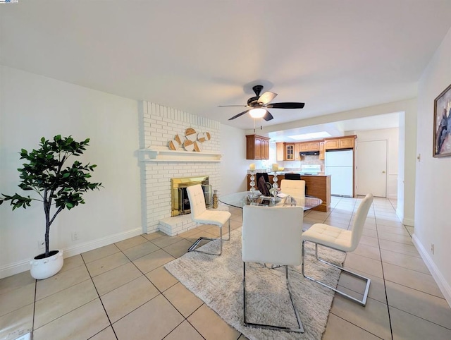 tiled dining space featuring ceiling fan and a fireplace