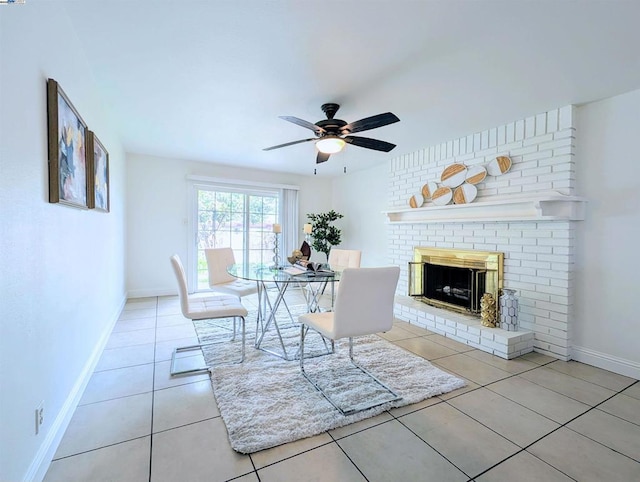 unfurnished dining area featuring light tile patterned flooring, ceiling fan, and a brick fireplace