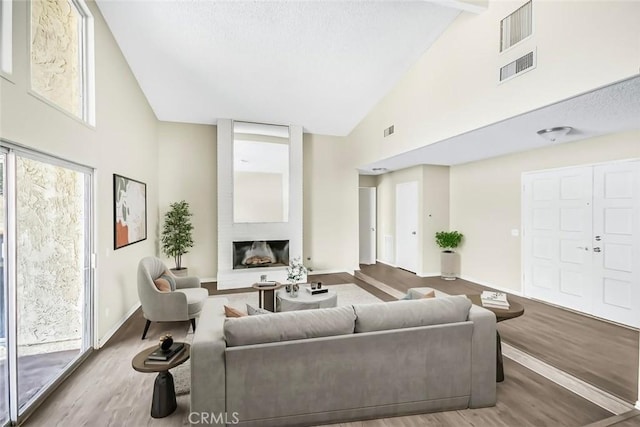 living room with high vaulted ceiling, light wood-type flooring, and a fireplace