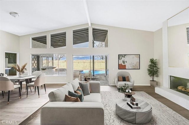 living room with high vaulted ceiling, hardwood / wood-style floors, and beam ceiling