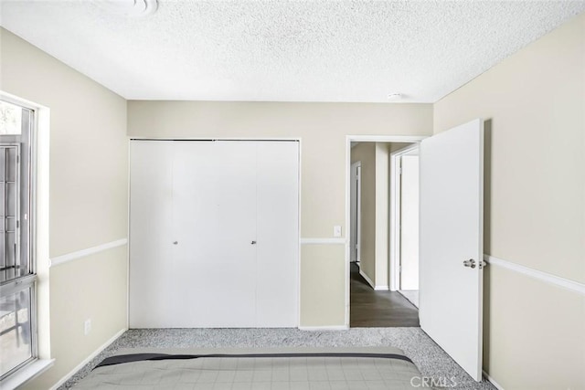 unfurnished bedroom featuring a textured ceiling and a closet