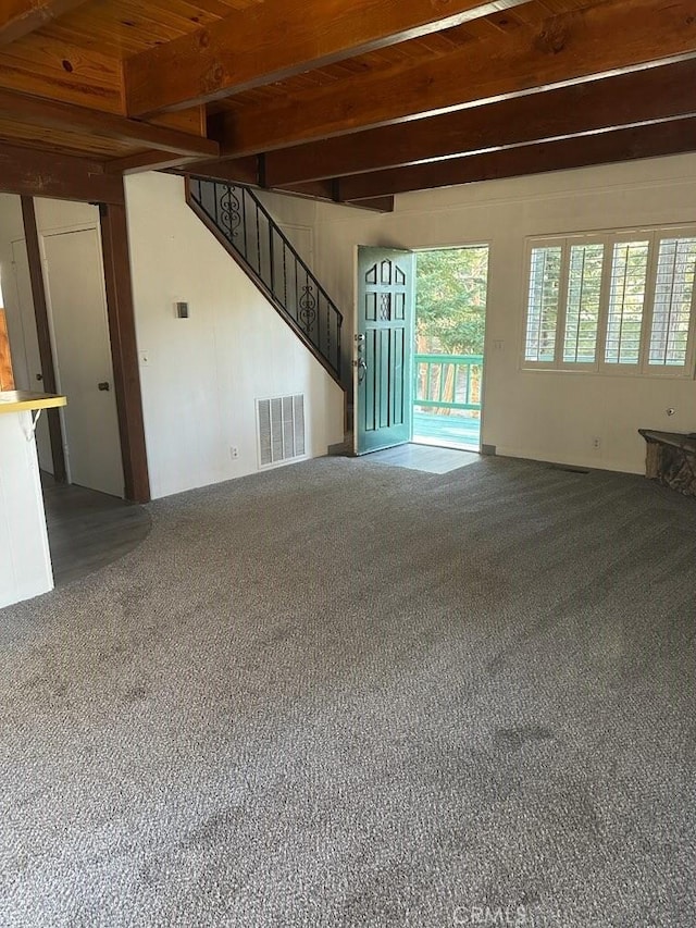 unfurnished living room with carpet floors and beamed ceiling