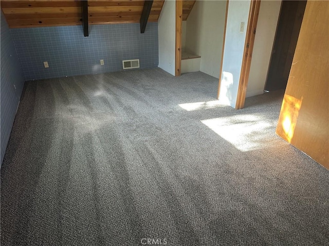 spare room featuring wood ceiling, beamed ceiling, and carpet flooring