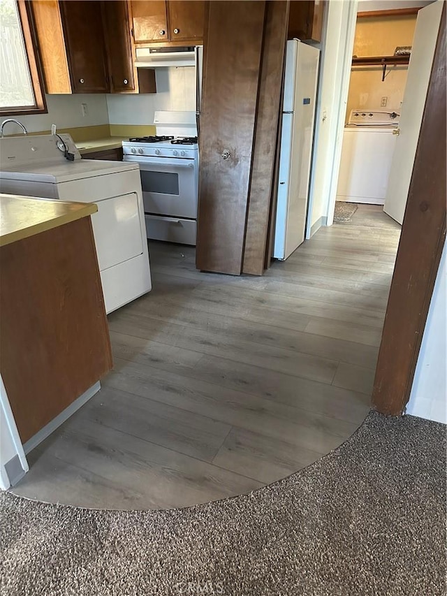 kitchen featuring white appliances, washer / dryer, exhaust hood, and light wood-type flooring