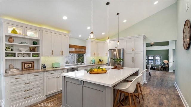 kitchen featuring a kitchen island, pendant lighting, white cabinetry, a kitchen bar, and stainless steel appliances