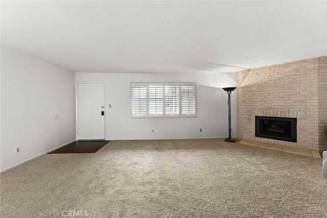 unfurnished living room with a brick fireplace and dark colored carpet