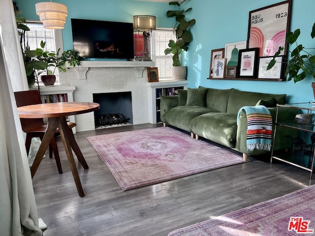 living room with a brick fireplace, hardwood / wood-style flooring, and a healthy amount of sunlight