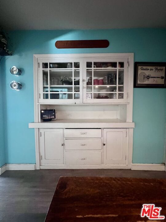 bar featuring white cabinets and dark hardwood / wood-style flooring