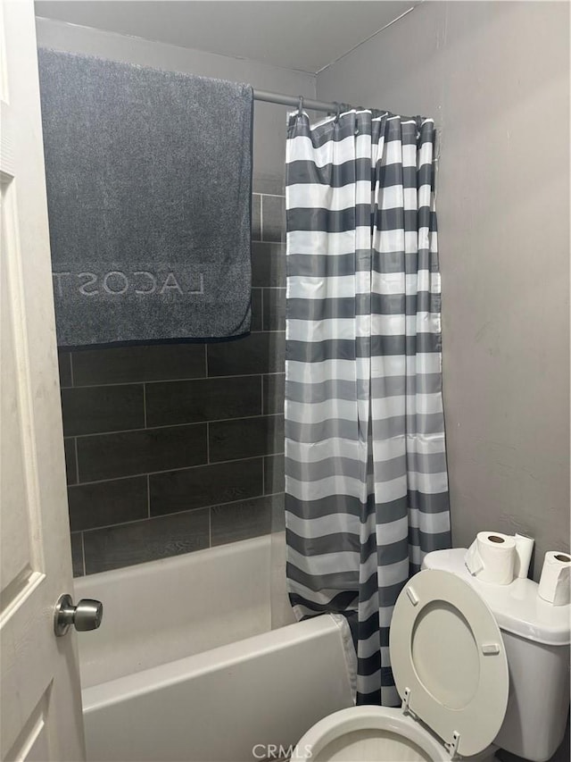 bathroom featuring shower / bathtub combination with curtain and toilet