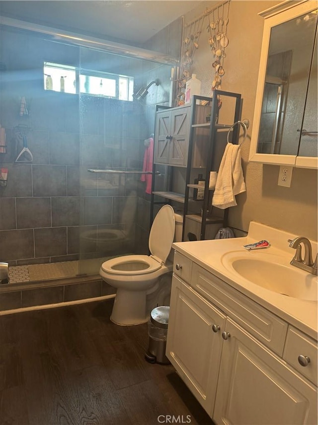 bathroom with vanity, a shower with shower door, hardwood / wood-style floors, and toilet