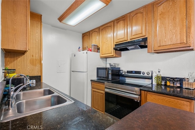 kitchen featuring white refrigerator, sink, stainless steel range with electric cooktop, and dark stone countertops