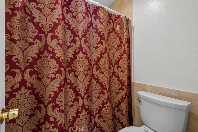 bathroom featuring toilet and tile walls