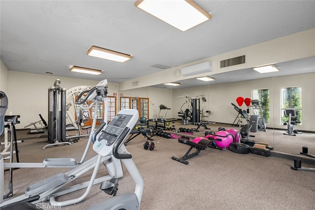 gym featuring a wall mounted air conditioner and a textured ceiling