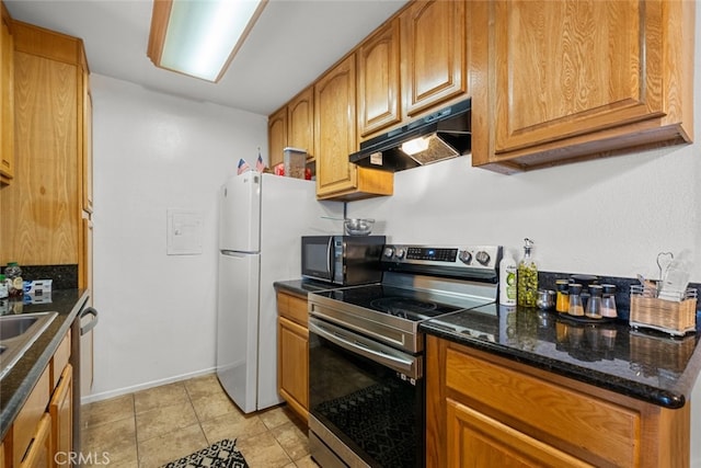 23515 Lyons Ave Unit 210, Valencia, CA 91355 - kitchen featuring appliances with stainless steel finishes, under cabinet range hood, brown cabinets, light tile patterned flooring, and dark stone countertops