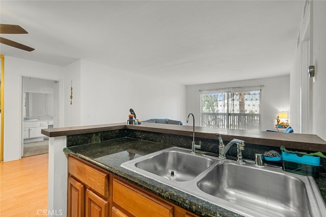 23515 Lyons Ave Unit 210, Valencia, CA 91355 - kitchen with brown cabinetry, light wood-style flooring, a ceiling fan, and dark stone countertops
