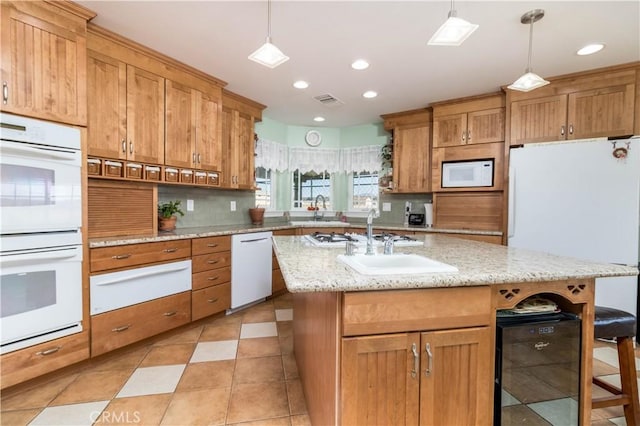 kitchen with an island with sink, a kitchen bar, white appliances, and decorative light fixtures