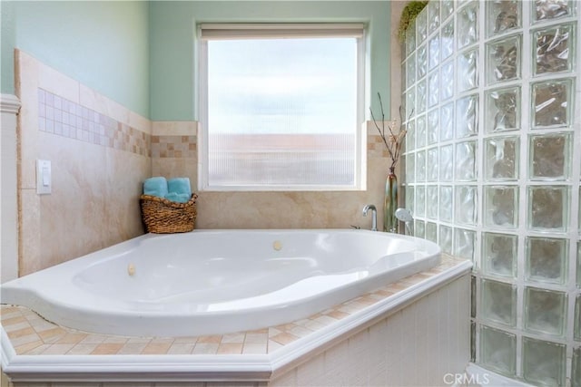 bathroom featuring a wealth of natural light and tiled bath