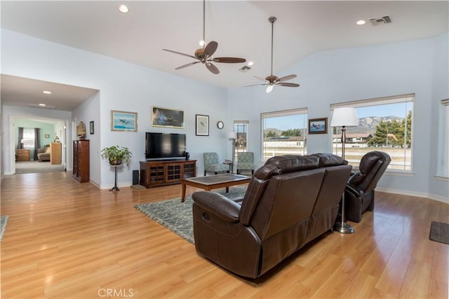 living room with high vaulted ceiling, light hardwood / wood-style floors, and a healthy amount of sunlight