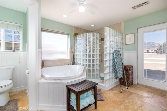 bathroom with tiled shower, plenty of natural light, and toilet