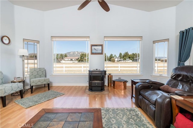 living room featuring vaulted ceiling, a wood stove, hardwood / wood-style floors, and ceiling fan