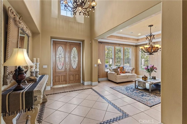 entrance foyer with a tray ceiling, an inviting chandelier, and light tile patterned floors