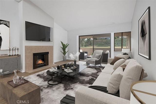 living room with hardwood / wood-style flooring, a tiled fireplace, and high vaulted ceiling