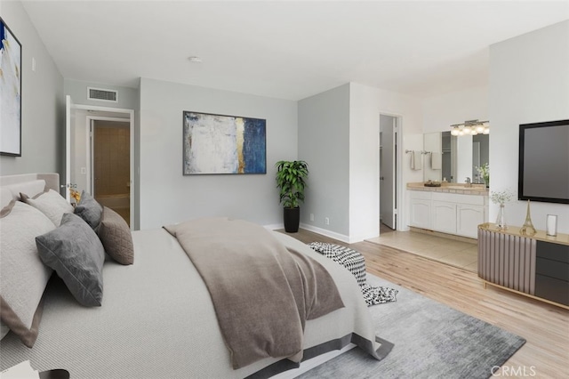 bedroom featuring light hardwood / wood-style flooring, a chandelier, and ensuite bathroom