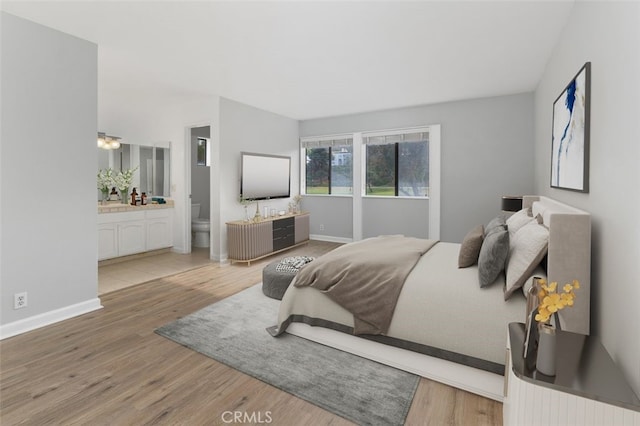 bedroom with connected bathroom and hardwood / wood-style flooring