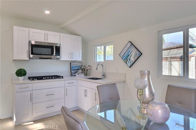 kitchen featuring lofted ceiling, sink, gas stovetop, and white cabinets