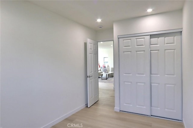 corridor with light wood-style floors, baseboards, and recessed lighting