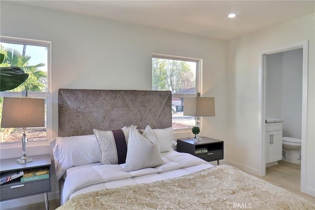 bedroom with ensuite bath and light hardwood / wood-style floors