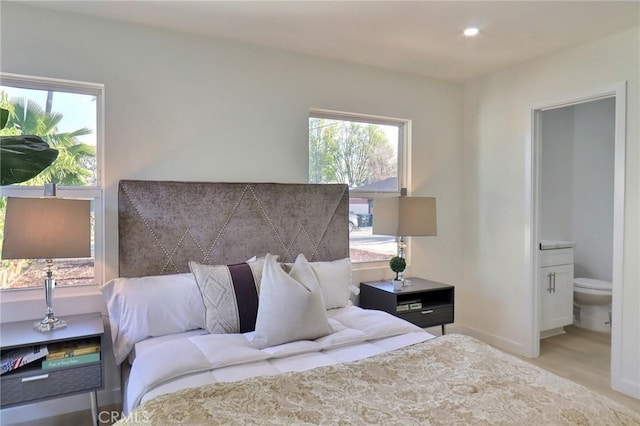 bedroom with multiple windows, connected bathroom, and wood finished floors