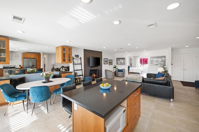 kitchen with a large fireplace, light tile patterned flooring, appliances with stainless steel finishes, and a kitchen island