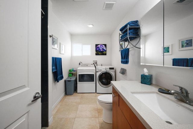 clothes washing area featuring sink, light tile patterned floors, and washer and clothes dryer