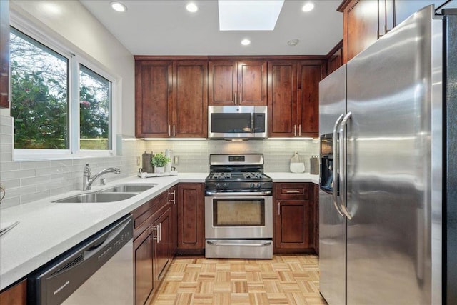 kitchen with stainless steel appliances, sink, backsplash, and a skylight