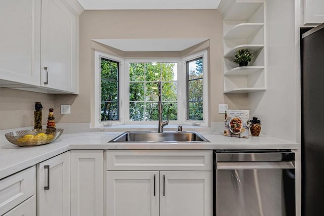 kitchen featuring sink, white cabinets, black fridge, stainless steel dishwasher, and light stone countertops