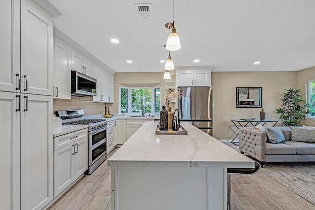 kitchen featuring white cabinetry, appliances with stainless steel finishes, a breakfast bar, and pendant lighting