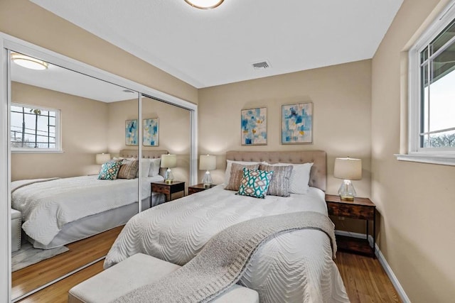 bedroom with multiple windows, hardwood / wood-style floors, and a closet