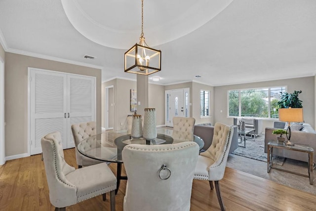 dining space featuring an inviting chandelier, light hardwood / wood-style flooring, and ornamental molding