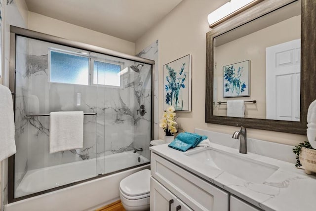 full bathroom featuring vanity, toilet, and combined bath / shower with glass door