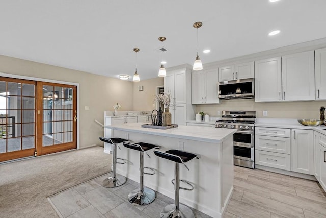 kitchen featuring white cabinetry, a center island, hanging light fixtures, a kitchen breakfast bar, and stainless steel appliances