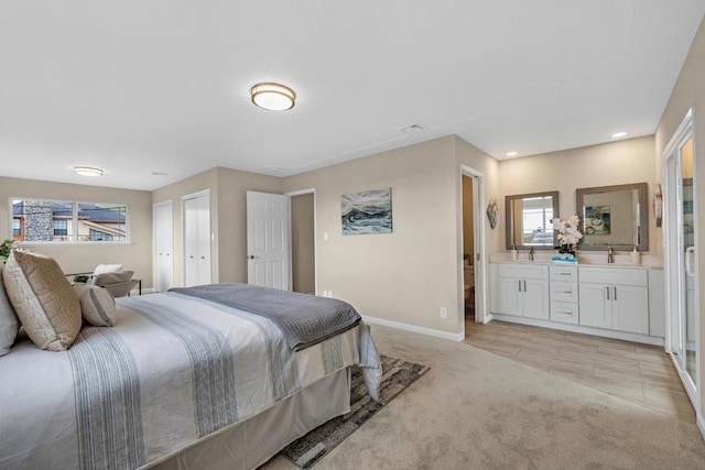 bedroom with light carpet, sink, and connected bathroom