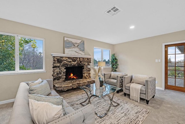 carpeted living room featuring a stone fireplace