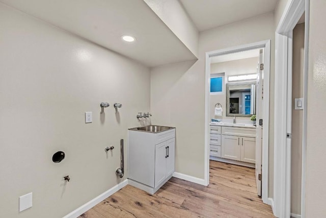 washroom with sink, hookup for a gas dryer, cabinets, and light wood-type flooring