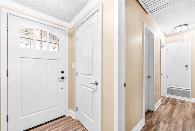 foyer entrance featuring hardwood / wood-style flooring, ornamental molding, and a textured ceiling